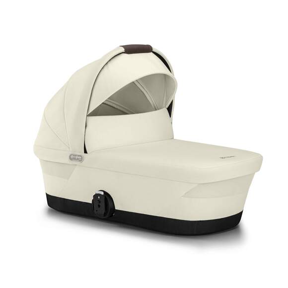 Kremfarget babybag med mørkbrunt håndtak og svart base, sett fra siden.